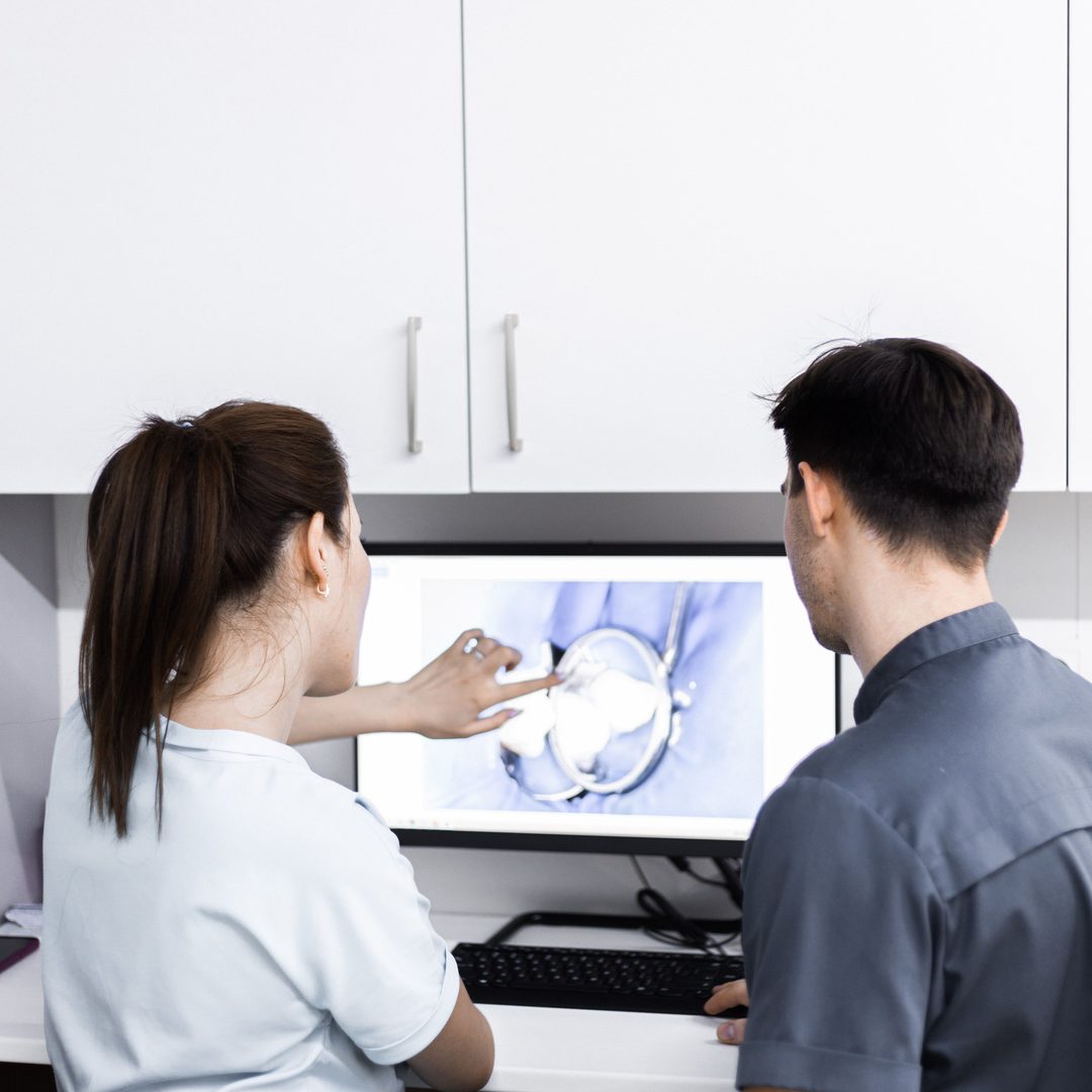 Implantes de carga inmediata - Clínica Dental Dentinos Dentista explica a un paciente una imagen dental en la pantalla de la consulta